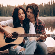 a woman playing an acoustic guitar next to a man who is hugging her