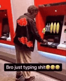 a man wearing a jacket with a cloud on it is typing on an atm machine .
