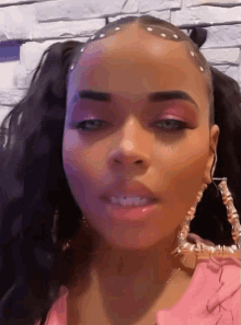 a woman wearing pink makeup and hoop earrings