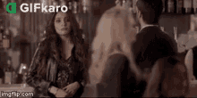 a man and a woman are standing next to each other in a bar talking to each other .
