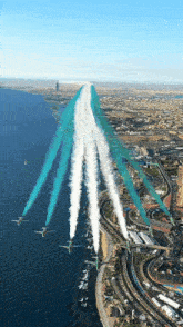 a group of planes are flying over a city near the water