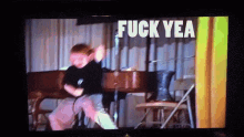 a young boy is dancing on a stage and the words fuck yea are on the screen behind him