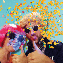 a man and a woman giving a thumbs up with confetti falling around them