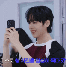 a young man is taking a picture of himself with a cell phone in front of a sign that says " 미소로 "