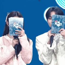 a man and a woman are covering their faces with cards that say ' christmas '
