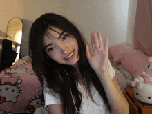 a girl waves her hand in front of a hello kitty bed