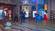 a group of people are dancing on a stage in front of a sign that says venga la alegria