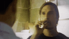 a man wipes his face with a napkin while another man looks on
