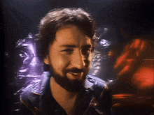 a man with a beard and a leather jacket smiles