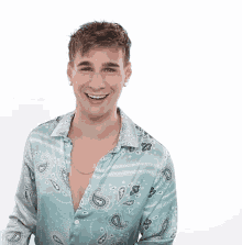 a young man wearing a paisley shirt and earrings smiles