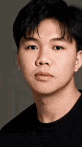 a close up of a young man 's face in a black shirt .