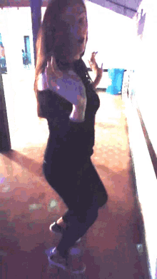 a woman in a black shirt is dancing in a room