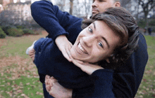 a man is carrying another man on his back and they are smiling for the camera
