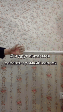 a person 's hand is reaching out towards a wall with a floral wallpaper