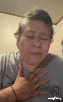 a woman wearing a grey shirt with the letter a on it is crying