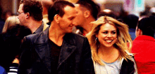 a man and a woman are walking down a crowded street and smiling .