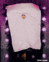 a person is wrapped in a pink blanket with a purple curtain behind them