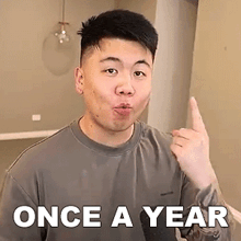 a man is making a funny face and pointing at the camera with the words `` once a year '' above him .
