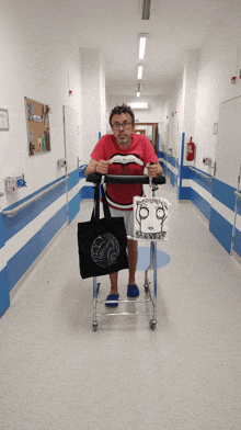 a man in a red shirt is pushing a walker in a hallway