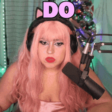 a woman with pink hair wearing headphones and a cat ear headband says do