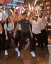 a group of people are dancing with their arms in the air in front of a sign that says ' apollo ' on it
