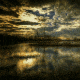 a dark cloudy sky over a body of water with trees in the background
