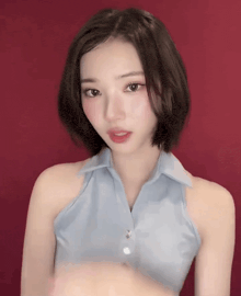a woman with short hair is wearing a blue shirt and red lipstick