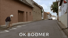 an elderly woman with a cane is walking down a street with the words ok boomer written on the road