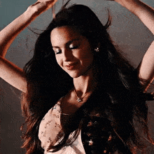 a woman in a floral dress is dancing with her hair in the air