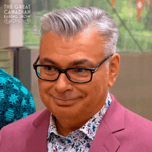 a man wearing glasses and a pink suit is smiling for the great canadian baking show