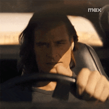a man is driving a car and the word max is on the bottom
