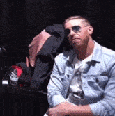 a man wearing sunglasses is sitting in a chair in a dark room .