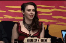 a woman in a red dress is sitting at a table with a sign that says rosaleen s. byrne