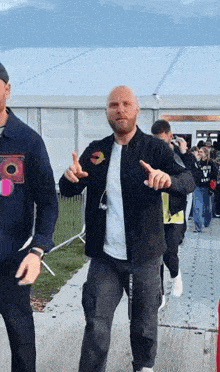 a bald man in a black jacket is dancing in front of a crowd