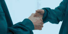 two people in blue sweatshirts are shaking hands in a room .