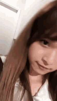 a close up of a woman 's face with long brown hair and a white shirt .