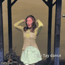 a woman in a plaid dress is dancing and the caption says tay tay dance