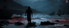 a gif of a man walking on a beach with devara gifs below him