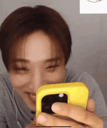 a man is holding a yellow cell phone in his hand