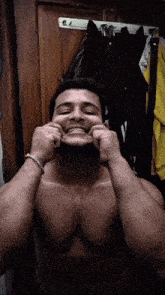 a shirtless man with a bracelet on his wrist is making a funny face
