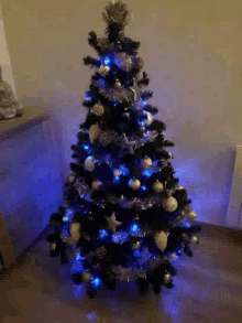 a black christmas tree with blue lights and silver ornaments