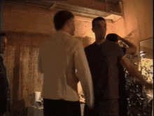 a group of men are standing in a room talking