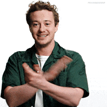 a man in a green shirt is clapping his hands in front of a white background