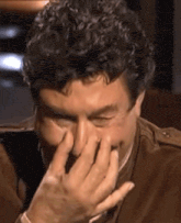 a close up of a man covering his face with his hands