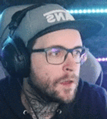 a man wearing glasses and headphones is wearing a hat .