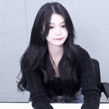 a woman with long black hair is wearing a black top