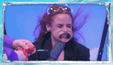 a woman wearing sunglasses makes a funny face while being sprayed with a water gun