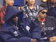 a group of people are sitting in a room and one of them is wearing an adidas jacket