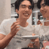 a man wearing a shirt that says aeer is holding a plate of food