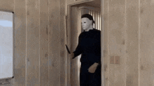 a man in a mask is holding a knife in a room .